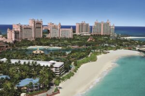 A beach with palm trees and buildings in the background.