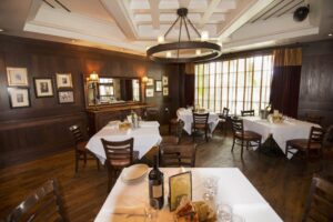 A restaurant with tables and chairs, a wine bottle on the table.