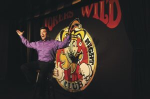 A man standing in front of a sign with an image of a mouse.