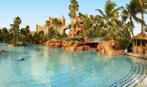 A pool with palm trees and a large building in the background.