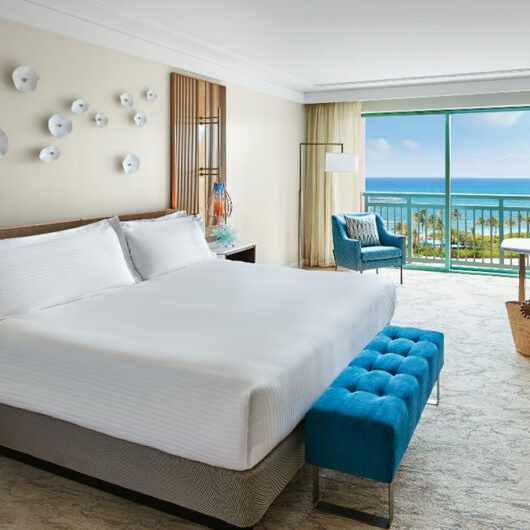 A bedroom with a view of the ocean and a bench.